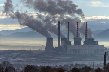 Power plant with smoking chimneys. Mountains in the background.. - 136311345