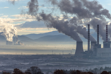 Power plant with smoking chimneys. Mountains in the background.. - 136311349