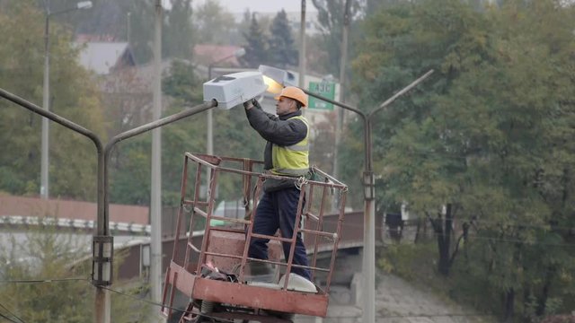 Repair of street lighting. Electrician changes a bulb on a street lamp