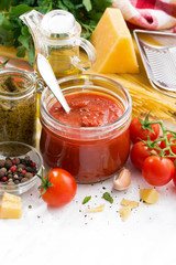 Fototapeta na wymiar tomato sauce, pesto and ingredients for pasta on a white table