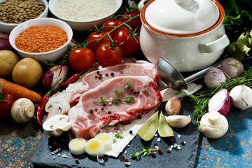 two pieces of raw pork and fresh ingredients for preparation
