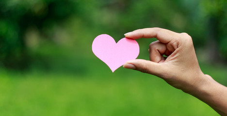 Hands holding heart against nature background