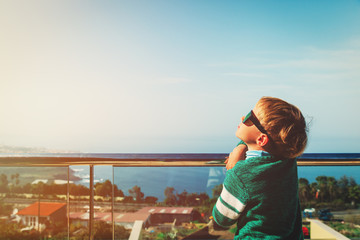 Fototapeta na wymiar little boy relaxed looking at sun on balcony at sea