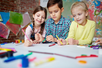 Creative children drawing with crayons in elementary school or kindergarten