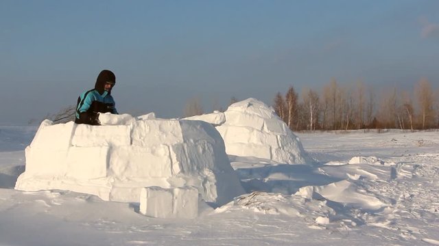 Man building an igloo  in a blizzard in the winter
