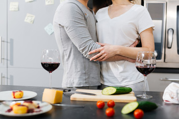 Bonding couple in embrace standing by kitchen table