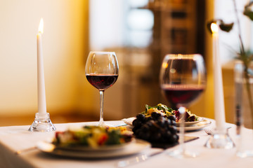 Served table with burning candles, red wine and fresh salad