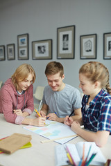Fototapeta premium Students writing on notepapers while discussing creative ideas
