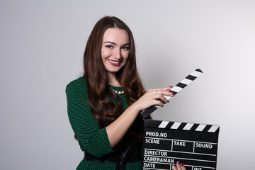 Beautiful young girl in green dress is holding a clapperboard