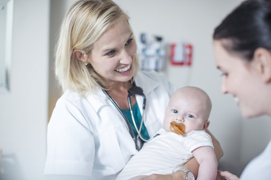 Female pediatrician holding baby at examination
