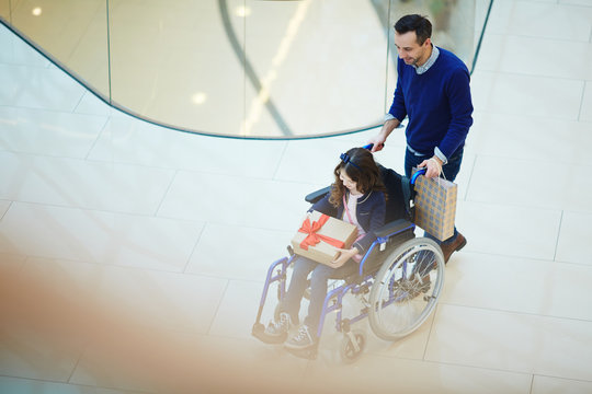 Young man pushing wheelchair with his daughter