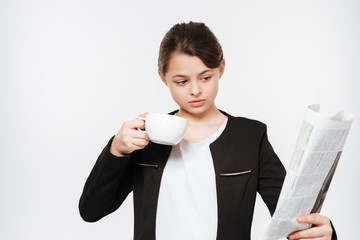 Amazing young girl drinking coffee reading gazette