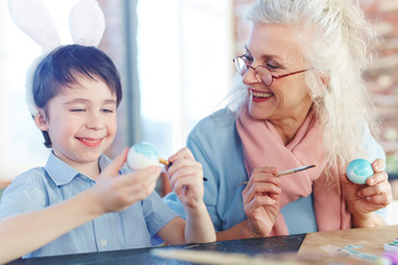 Obraz na płótnie Canvas Senior female and her grandsone painting Easter eggs
