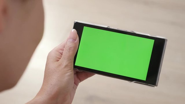 Female holds green screen mobile device 4K 2160p 30fps UltraHD footage - Surfing on Internet while lying on floor with greenscreen smart phone 3840X2160 UHD video 