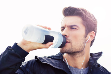 Handsome man in headphones drinking water