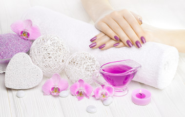 Plakat beautiful pink manicure with orchid and towel on the white wooden table. spa