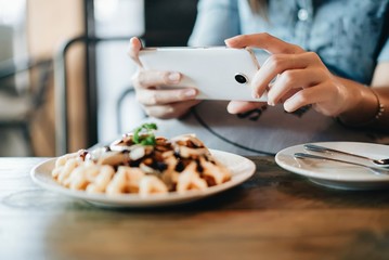 Hands of woman taking a photo of breakfast with smartphone.