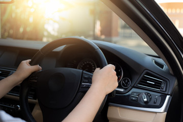 Woman hand holding steering wheel with sunlight