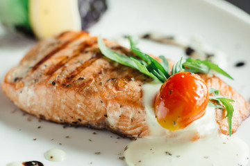 Baked salmon fillet on a white plate on a wooden table