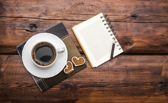 Coffee cup and note book on wooden tabletop