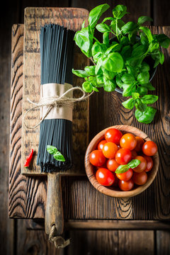 Prepartion for black spaghetti made of tomatoes and basil