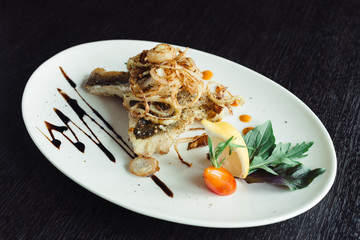 Walleye on the grill with onions on a white plate on a wooden table