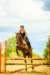 Jockey young girl doing horse jumping through hurdle