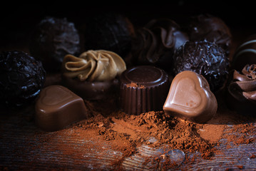Chocolate pralines and cocoa powder on dark wood as a love gift