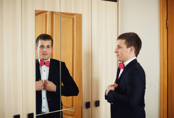 groom looking in the mirror wearing jacket