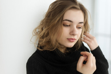 Naklejka premium portrait of beautiful young woman with makeup posing by window