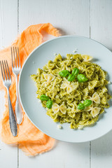 Tasty pasta with green pesto and basil on white table