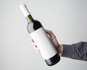Hand is holding wine bottle