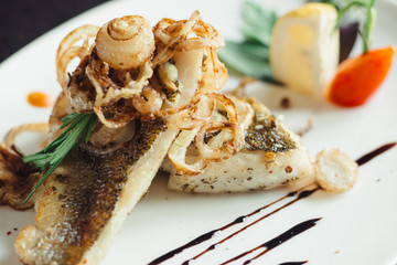 Walleye on the grill with onions on a white plate on a wooden table
