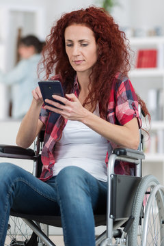 handicapped redhead woman texting and surfing on her smartphone