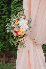 Beautiful wedding archway. Arch decorated with peachy cloth and flowers