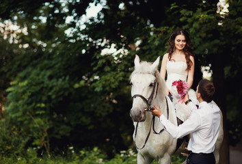 Bride o the luxury white horse recieving flowers from groom