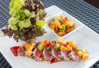 Grilled tuna steak slices with mango salsa and vetgetable salad