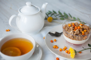 Serving table for breakfast: tea with lemon, granola and tea pot.