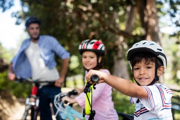 Father and children standing with bicycle in park