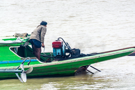 Burmese Man Starting The Engine Of Homemade Motor Boat, Irrawaddy Delta, Myanmar