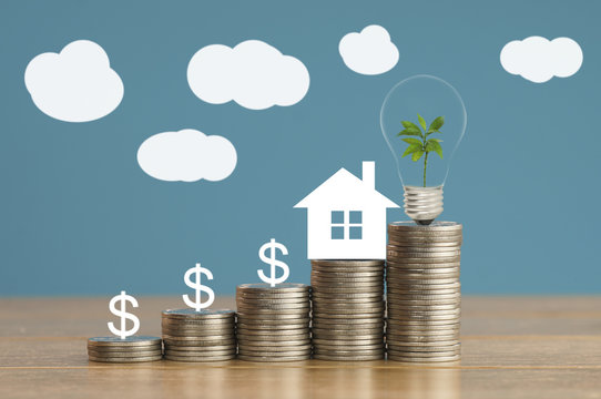 pile of coins and house paper with green small tree, light bulb on money, concept in save, finance and grow of business about home
