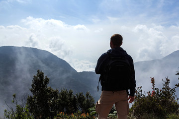 Naklejka premium Backpacker looking at misty mountains