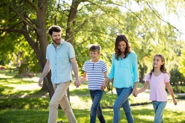Happy family with hand in hand walking in park