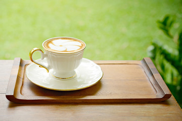 Coffee cup of hot latte art on table wood in garden