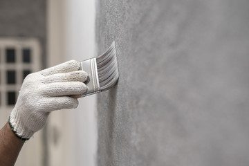 hand of worker use brush for color paint concrete Loft style on wall - obrazy, fototapety, plakaty