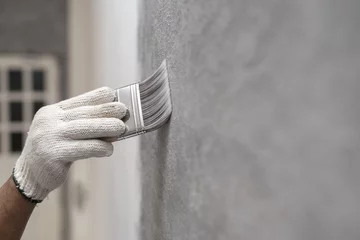 Fotobehang hand of worker use brush for color paint concrete Loft style on wall © bannafarsai