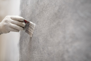 hand of worker use brush for color paint concrete Loft style on wall