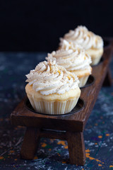 Homemade vanilla cupcakes with lemon cream cap on a dark background. Selective focus.