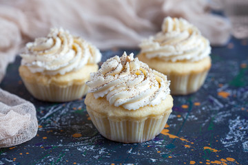 Homemade vanilla cupcakes with lemon cream cap on a dark background. Selective focus.