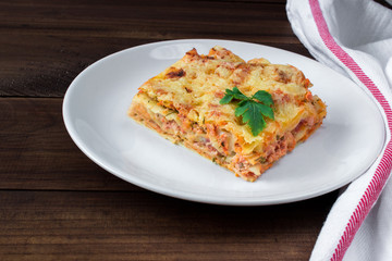Close-up of a traditional lasagna topped with parskey leafs served on a white plate